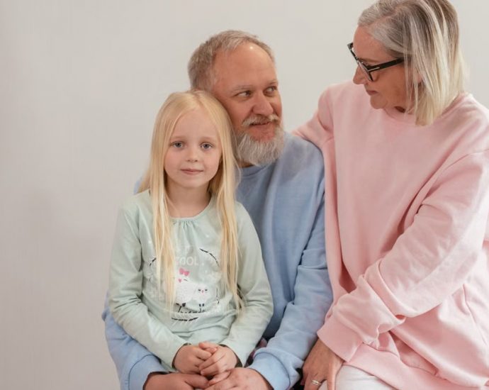 Grandparents lovingly embrace their granddaughter in a bright, studio setting, capturing family warmth and connection.