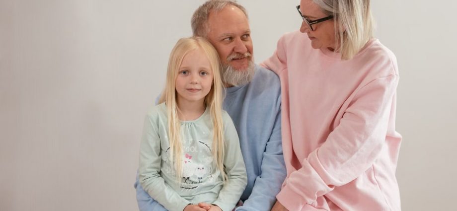Grandparents lovingly embrace their granddaughter in a bright, studio setting, capturing family warmth and connection.