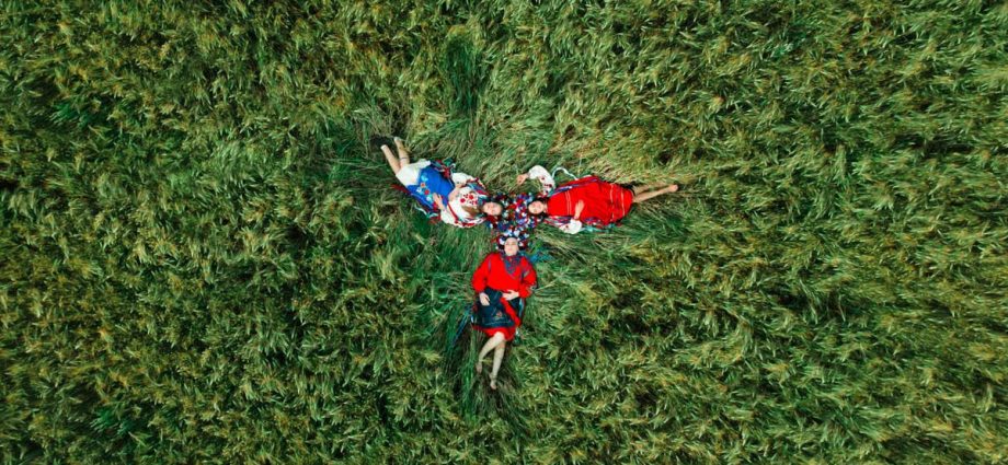 A group relaxing in traditional clothing on a grassy field, captured from above.