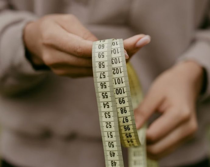 Hands holding a yellow tape measure, perfect for concepts like construction or sewing.