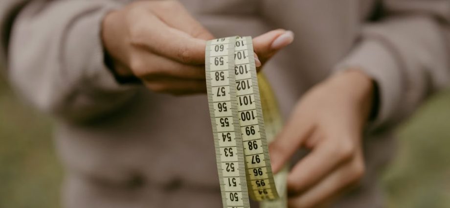 Hands holding a yellow tape measure, perfect for concepts like construction or sewing.